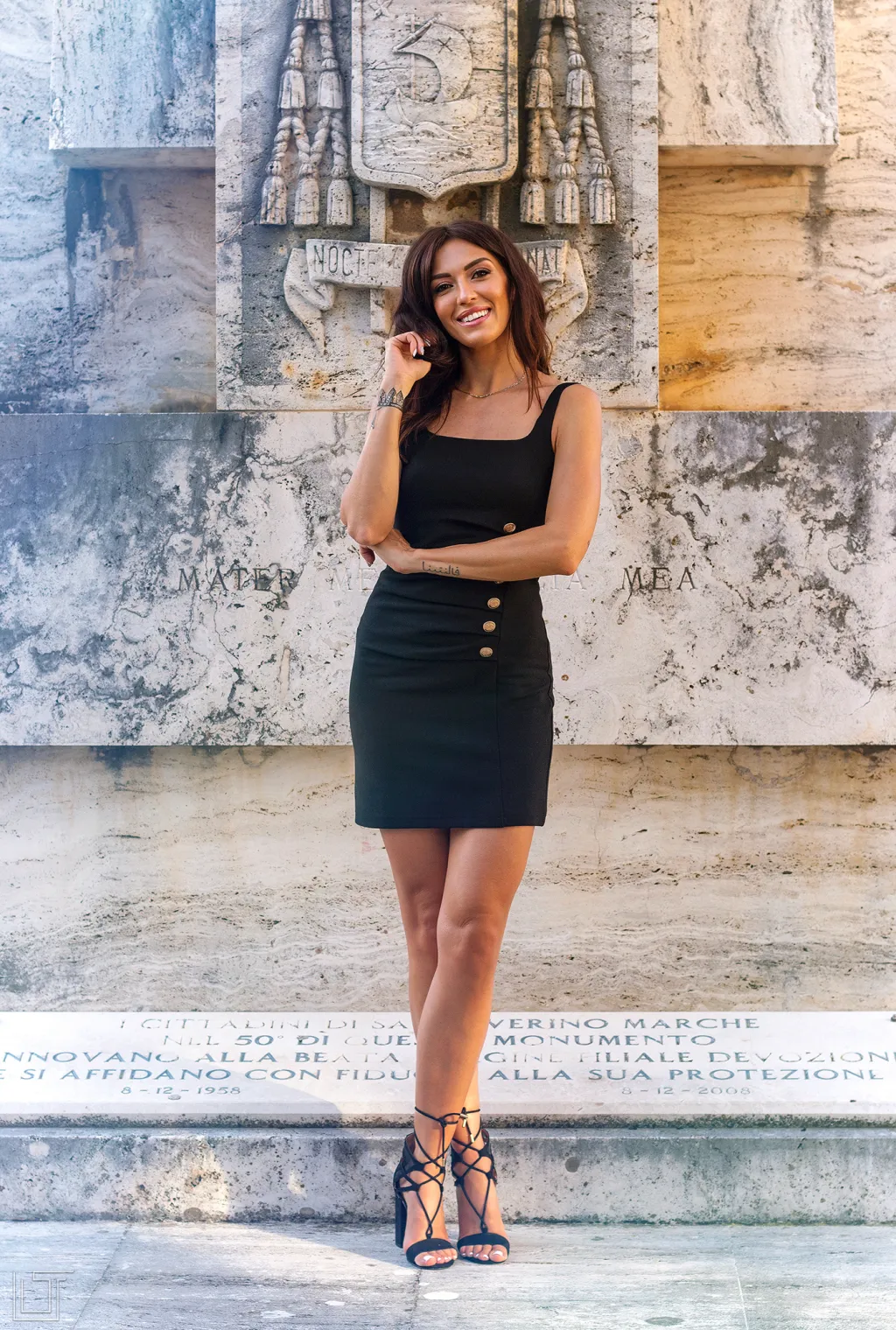 Portrait of a young woman in a black dress in front of a marble monument