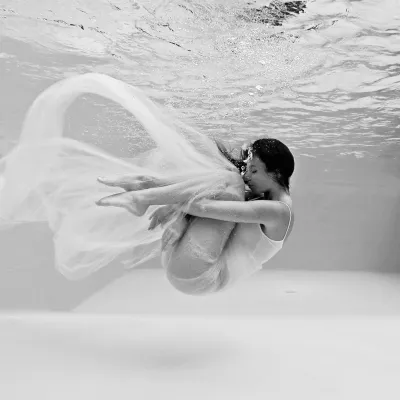 Suspended between breath and stillness. A figure curls beneath the surface, wrapped in fabric that drifts like a whispe…
